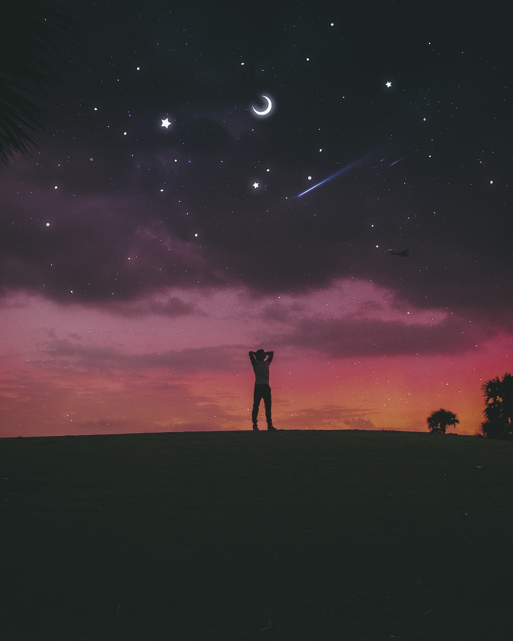 A figure stands silhouetted against dawn breaking with a night sky overhead.